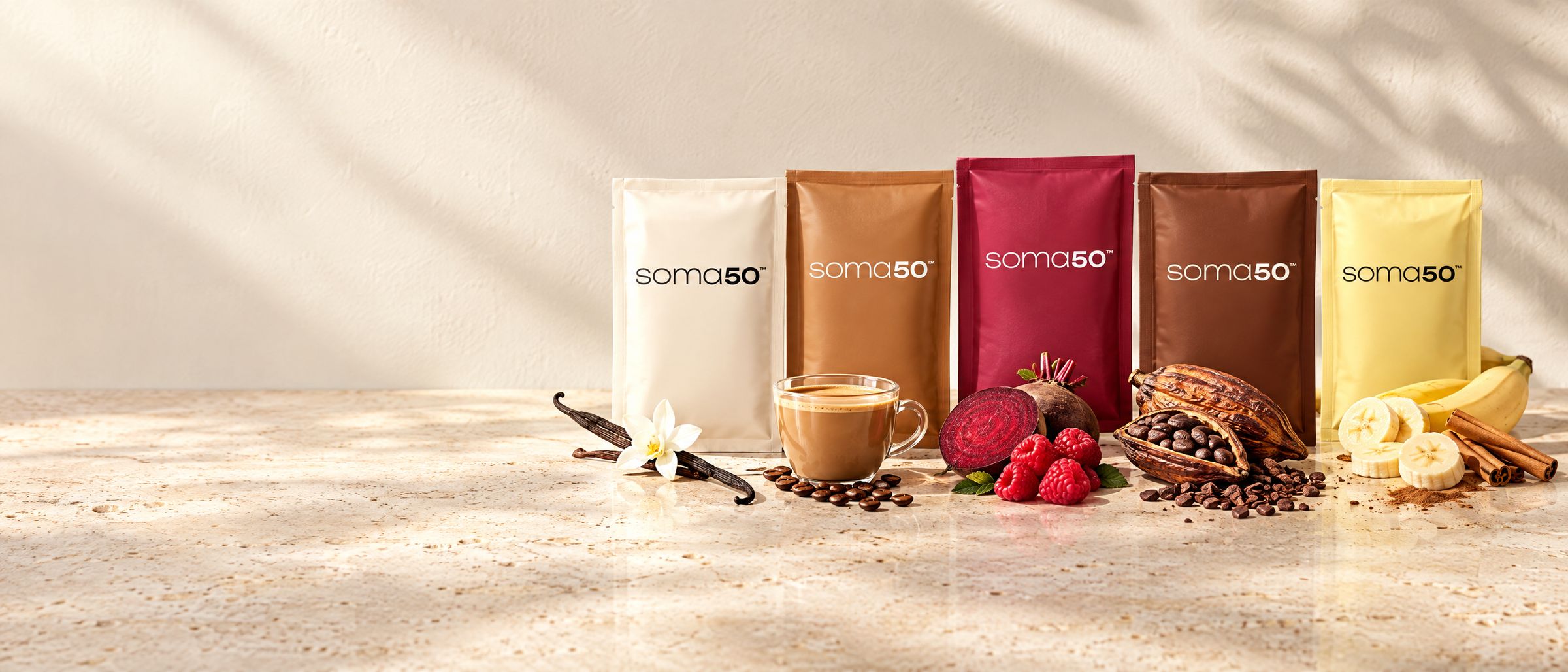 Cinco sachês da SOMA em fila, nas cores creme, caramelo, magenta, cacau e amarelo, com baunilha, café com leite, beterraba e framboesas, cacau e banana com canela à frente.